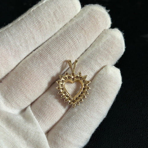 Gold pendant with a decorative design on a white cloth against a dark background